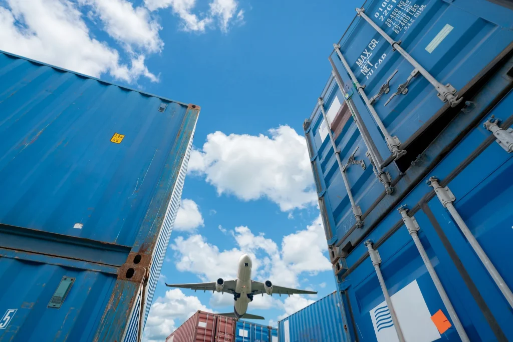 Airplane flying above logistic container. Air logistics. Cargo and shipping business. Container